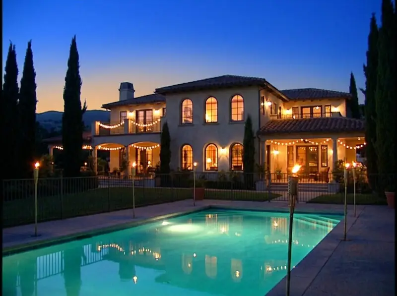 Villa Serena at dusk: a Spanish-style mansion with a lit pool and cypress trees